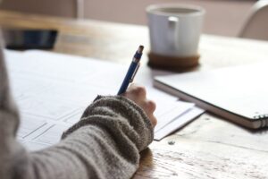 woman writing in a journal next to a mug of coffee